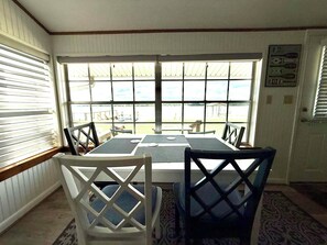 Espaço de refeições com mesa, cadeiras, janelas amplas e vista para o exterior.