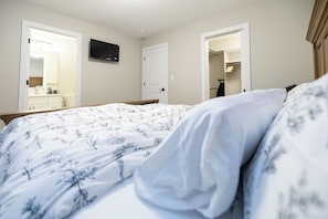 Een slaapkamer met een bed, een televisie aan de muur en een deur naar een badkamer.