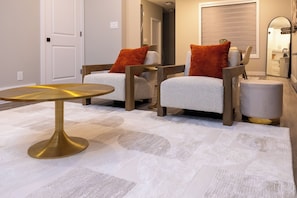 A modern living room with a round table, two armchairs, and a small ottoman. - Hebron Place | Elegant 3-Bedroom Stay for 6 (Regina)