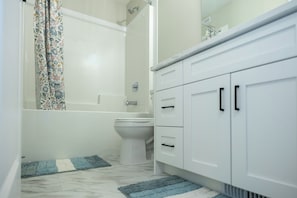 Een badkamer met toilet, douche en een wastafel met kastjes.
