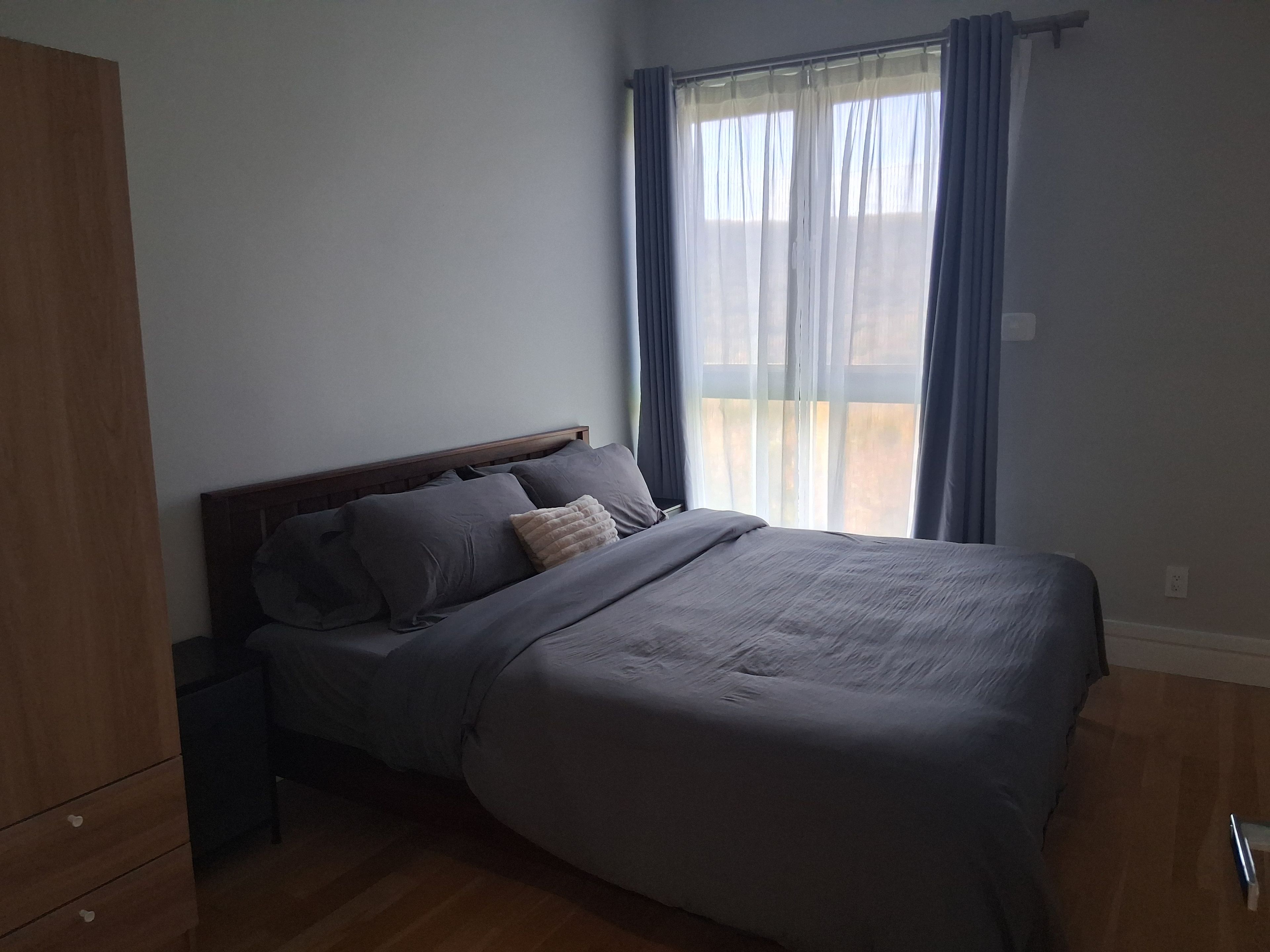 Una camera da letto con un letto, un comodino, un armadio e una finestra con tende.