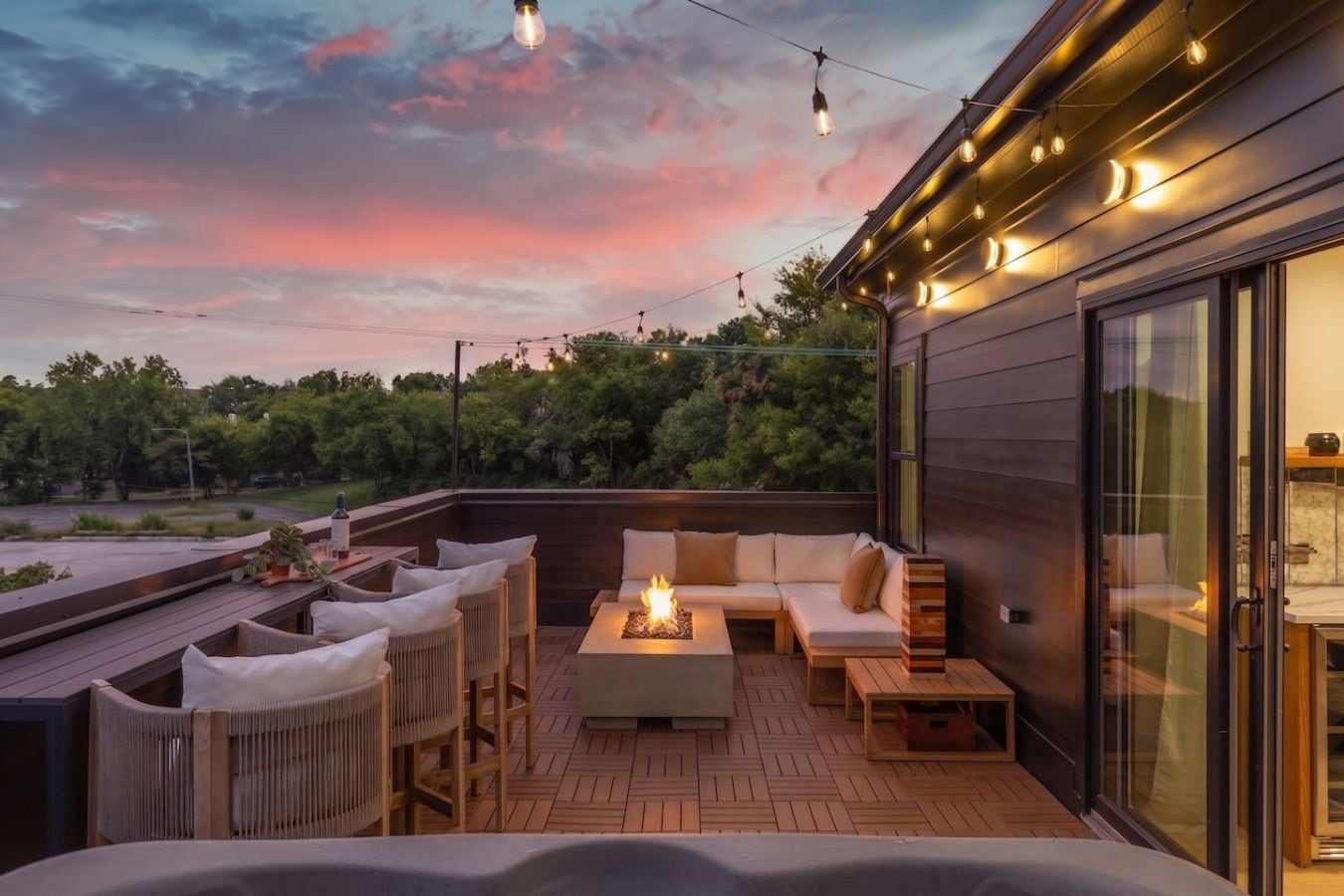 An outdoor deck with a fire feature, seating area, and string lights.