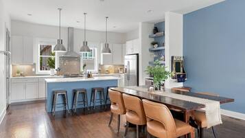 A modern kitchen with a central island, bar stools, pendant lighting, and a blue accent wall.