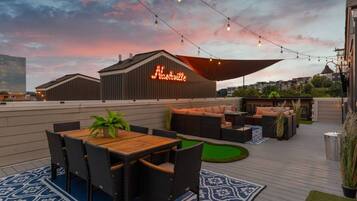 An outdoor patio with a dining area, seating, and a neon sign.