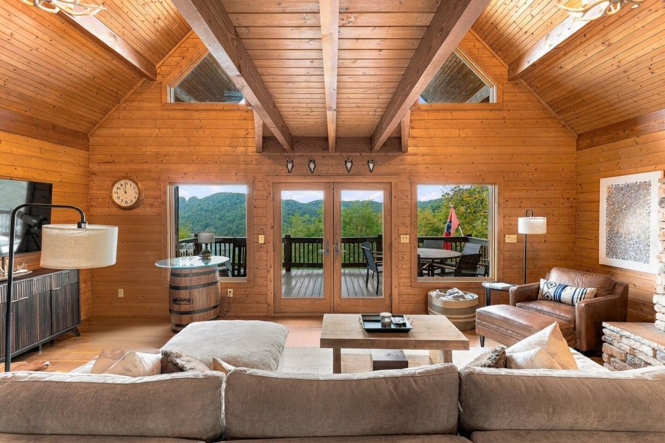 A log cabin interior with a sofa, coffee table, and a view through the doors.