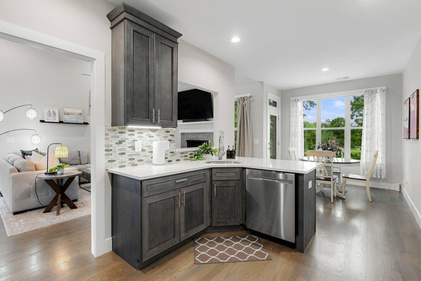 A modern kitchen with dark cabinetry, a white countertop, and a built-in dishwasher.