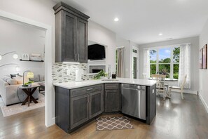 Una cocina moderna con armarios oscuros, una encimera blanca y un lavavajillas empotrado.