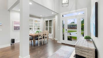 A spacious hallway with a dining area, a fireplace, and a view of the outside.