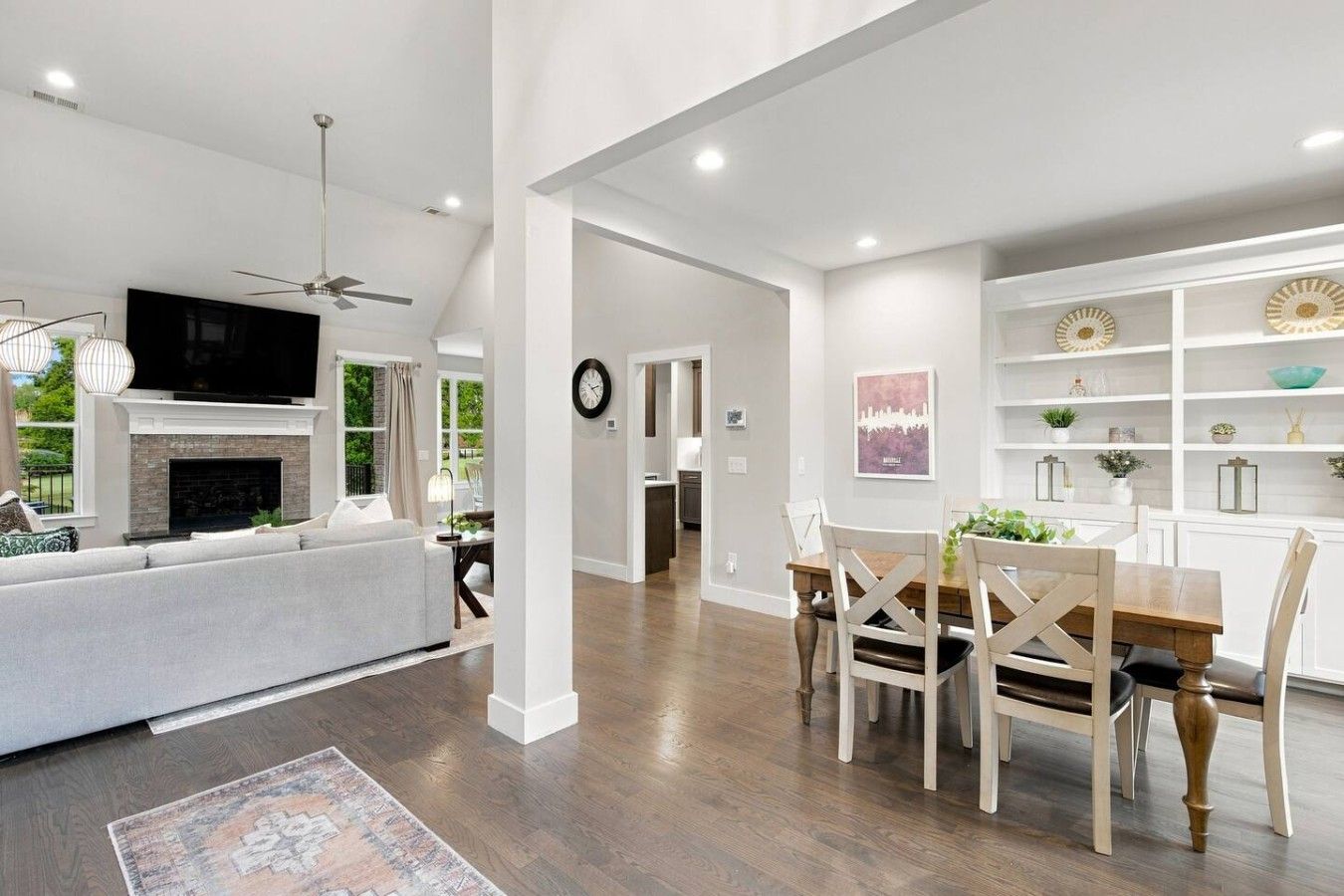 A spacious living area with a fireplace, a dining table with chairs, and a kitchen in the background.