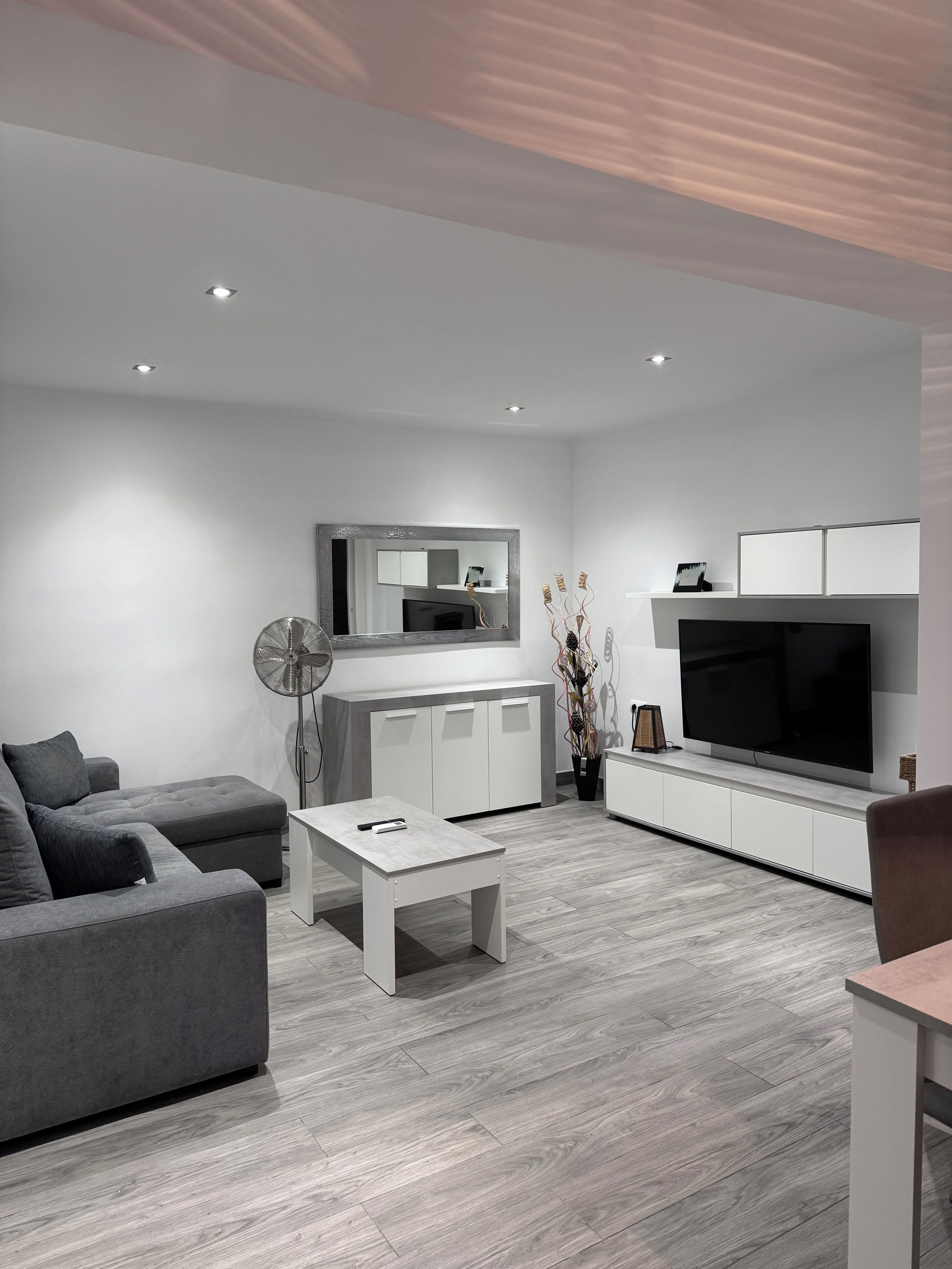 A modern living room with a grey sofa, a coffee table, a TV, and a cabinet.