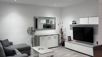 A modern living room with a grey sofa, a coffee table, a TV, and a cabinet.
