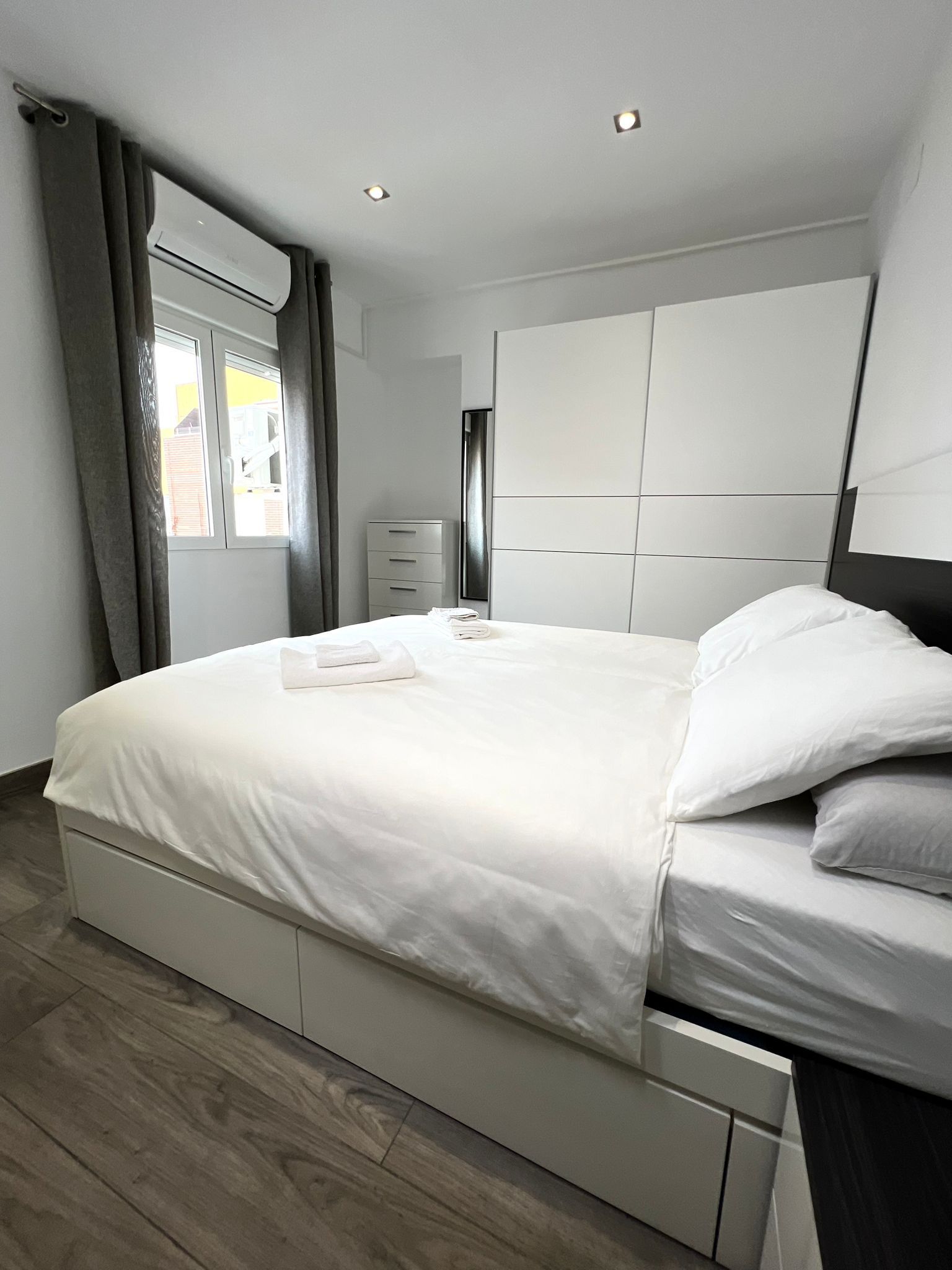 Una camera da letto moderna con un letto grande, un comodino, un armadio e una finestra con tende.