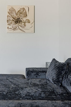 Een kamer met een bank en een kunstwerk aan de muur.