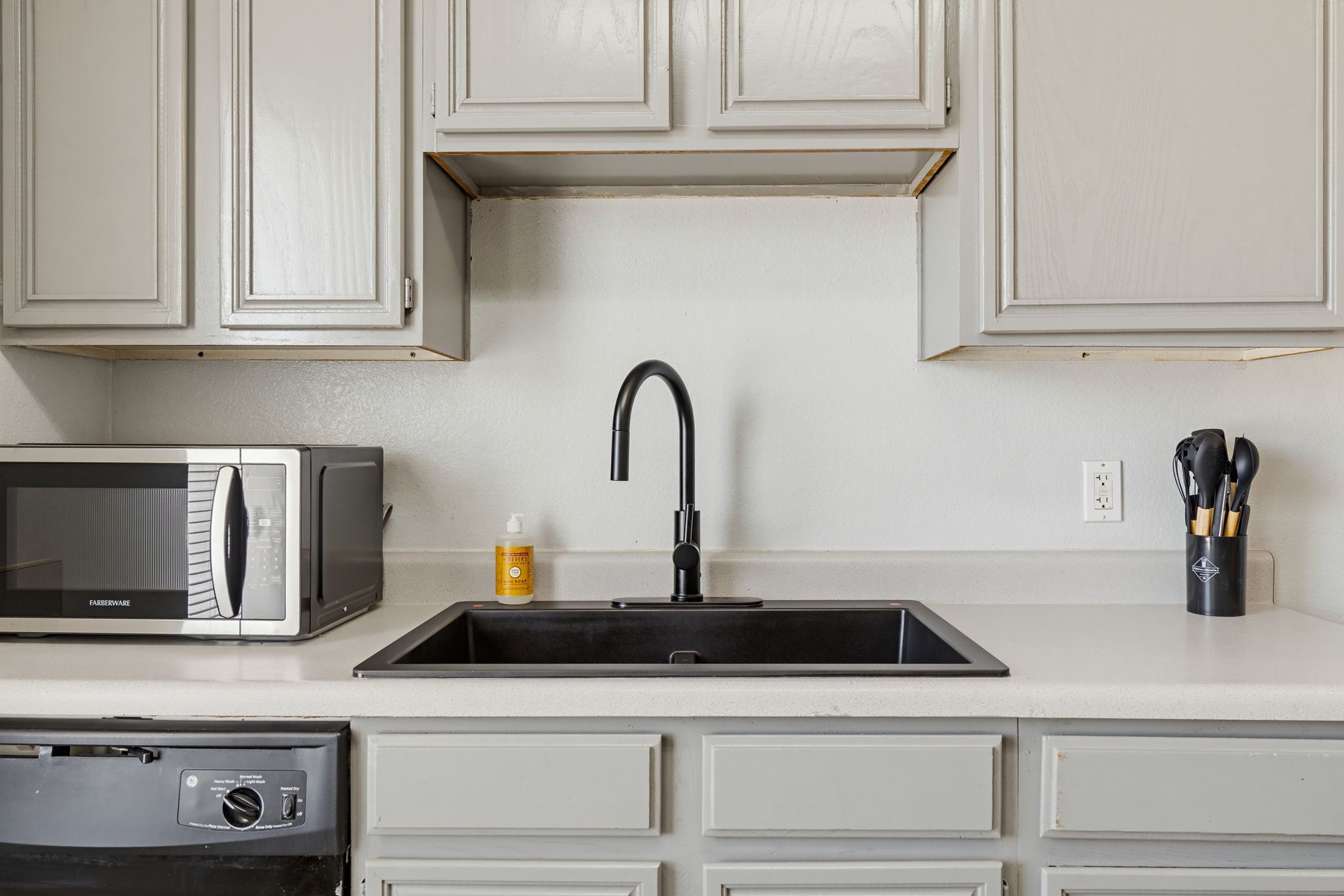 Una cocina con microondas, un lavabo con grifo moderno y un escurreplatos.
