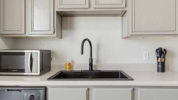 Una cocina con microondas, un lavabo con grifo moderno y un escurreplatos.