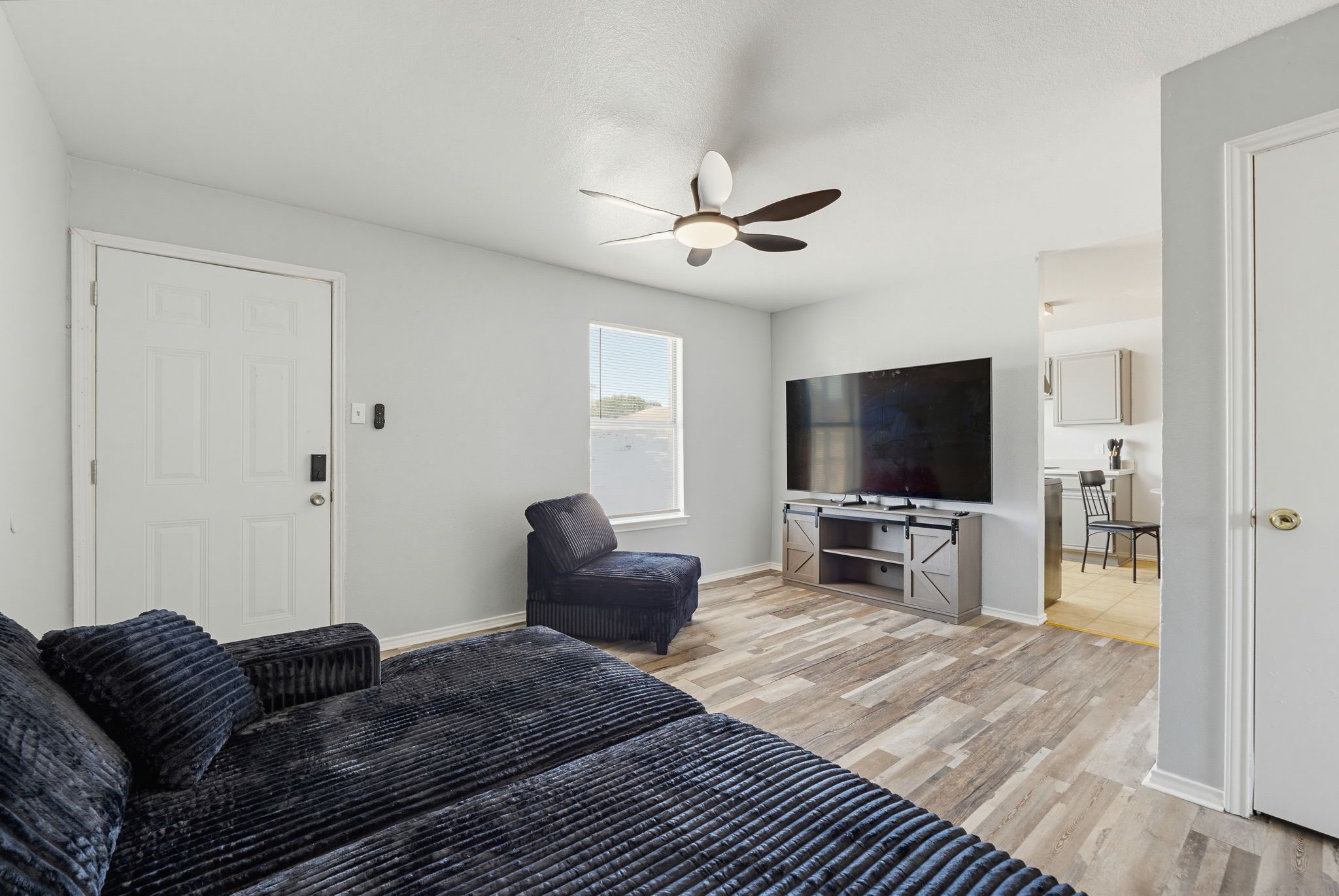 A bedroom with a bed, a ceiling fan, a TV, and a desk with a chair.