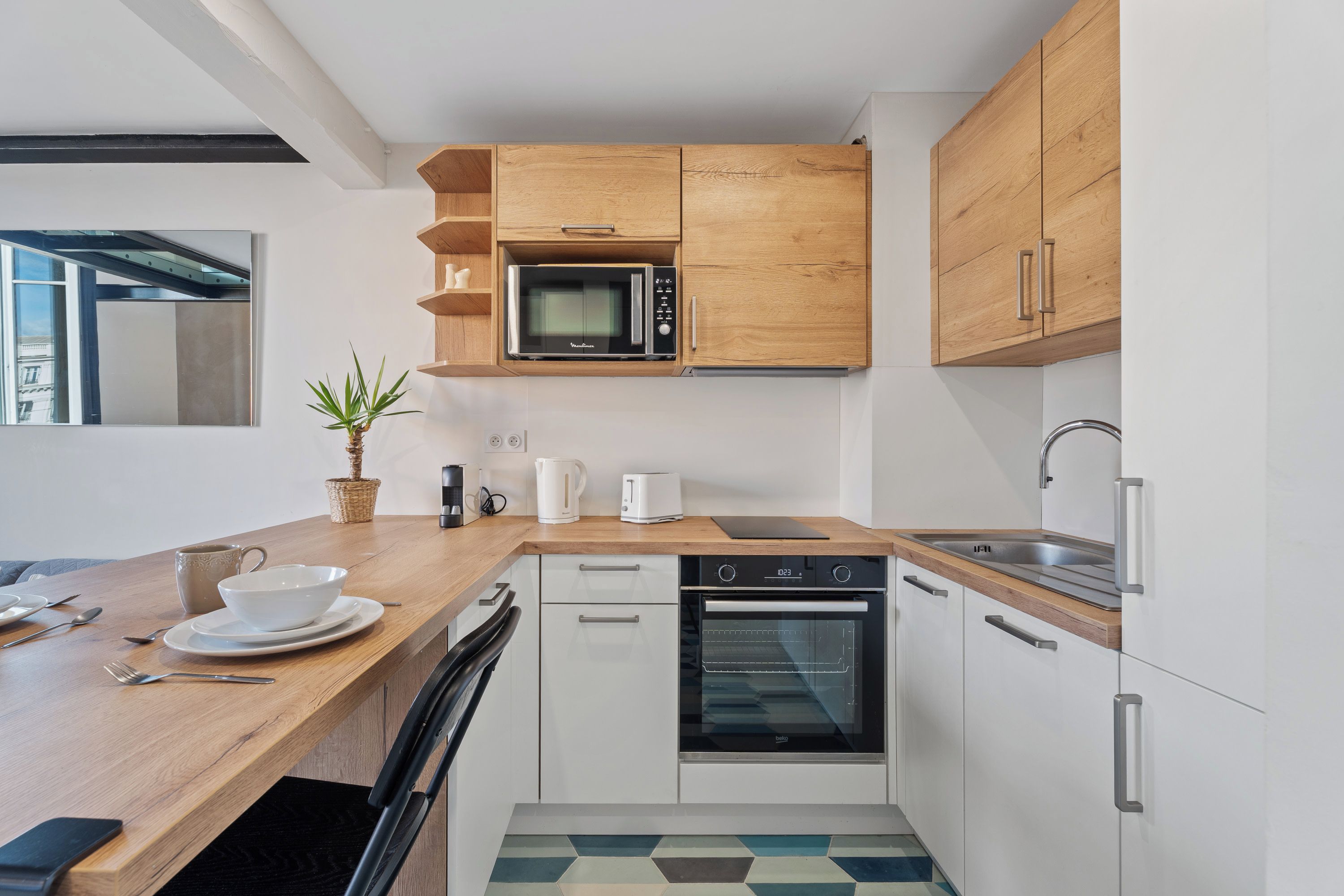A modern kitchen with wooden cabinets, a microwave, a kettle, and a dishwasher.