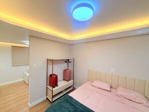 Ein Hotelzimmer mit Bett, Kleiderschrank, Gepäckhaken und Deckenleuchte.