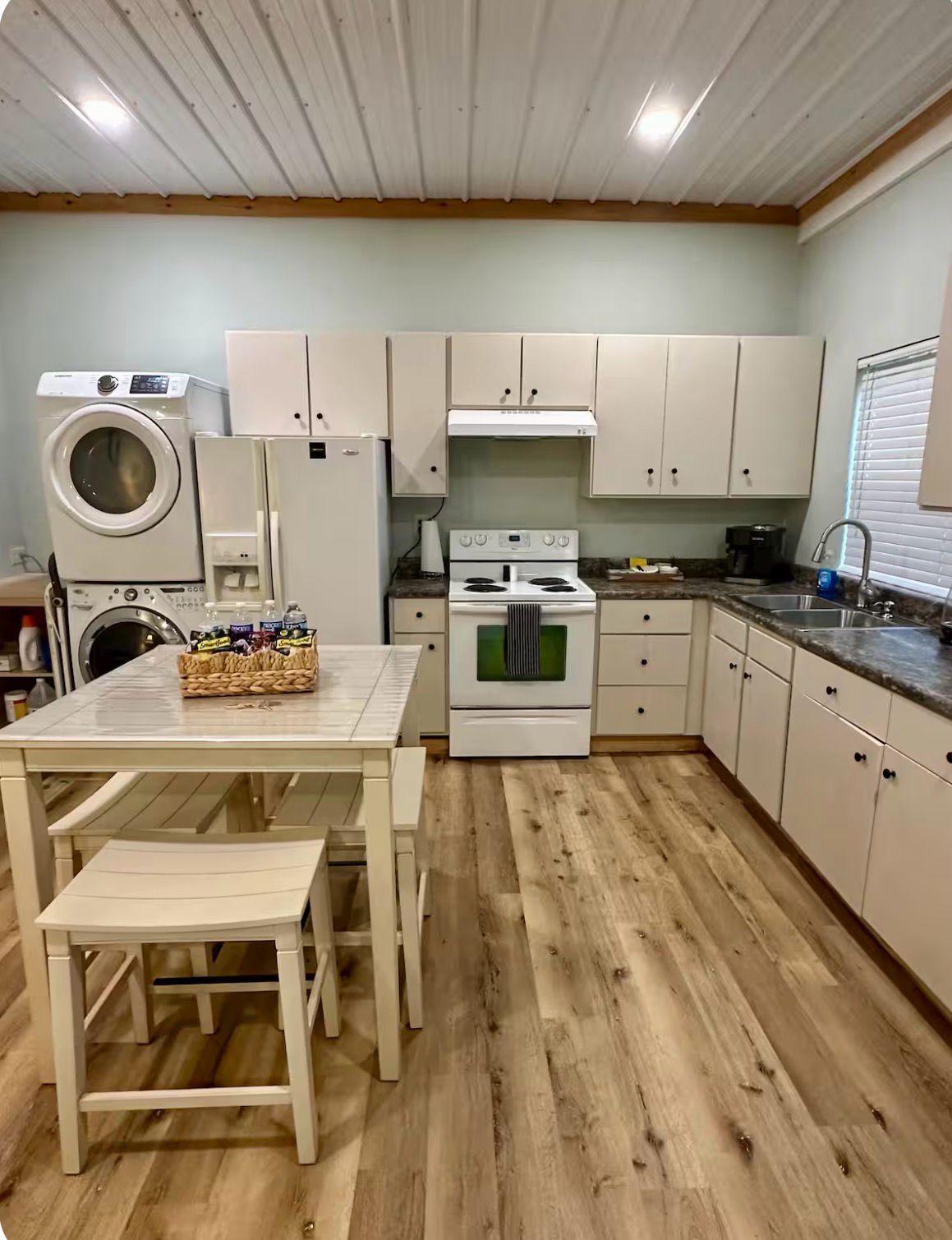 A compact kitchen with a washing machine, a stove, and a sink.