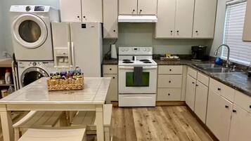 A compact kitchen with a washing machine, a stove, and a sink.