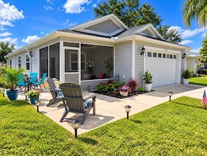 A single-story house with a covered porch, a patio with outdoor furniture, and a well-maintained lawn. - Paradise in Spanish Springs 2/2/1.5 garage w/ 4-seat gas golf cart. Pet friendly (Lady Lake)