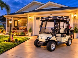 A golf cart parked in front of a house with a garage, number 716, and a well-lit porch with outdoor seating. - Paradise in Spanish Springs 2/2/1.5 garage w/ 4-seat gas golf cart. Pet friendly (Lady Lake)