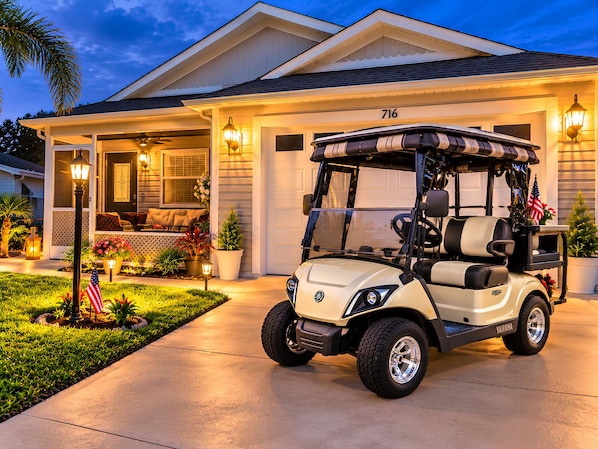 A golf cart parked in front of a house with a garage, number 716, and a well-lit porch with outdoor seating. - Paradise in Spanish Springs 2/2/1.5 garage w/ 4-seat gas golf cart. Pet friendly (Lady Lake)