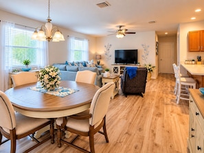 A modern living room with a dining area, a flat-screen TV, and a ceiling fan. - Paradise in Spanish Springs 2/2/1.5 garage w/ 4-seat gas golf cart. Pet friendly (Lady Lake)