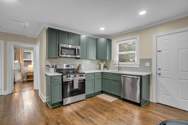 A kitchen with a built-in microwave, stainless steel appliances, and green cabinetry.