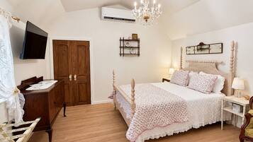 Een slaapkamer met een houten bed, een bureau, een televisie en een kroonluchter.