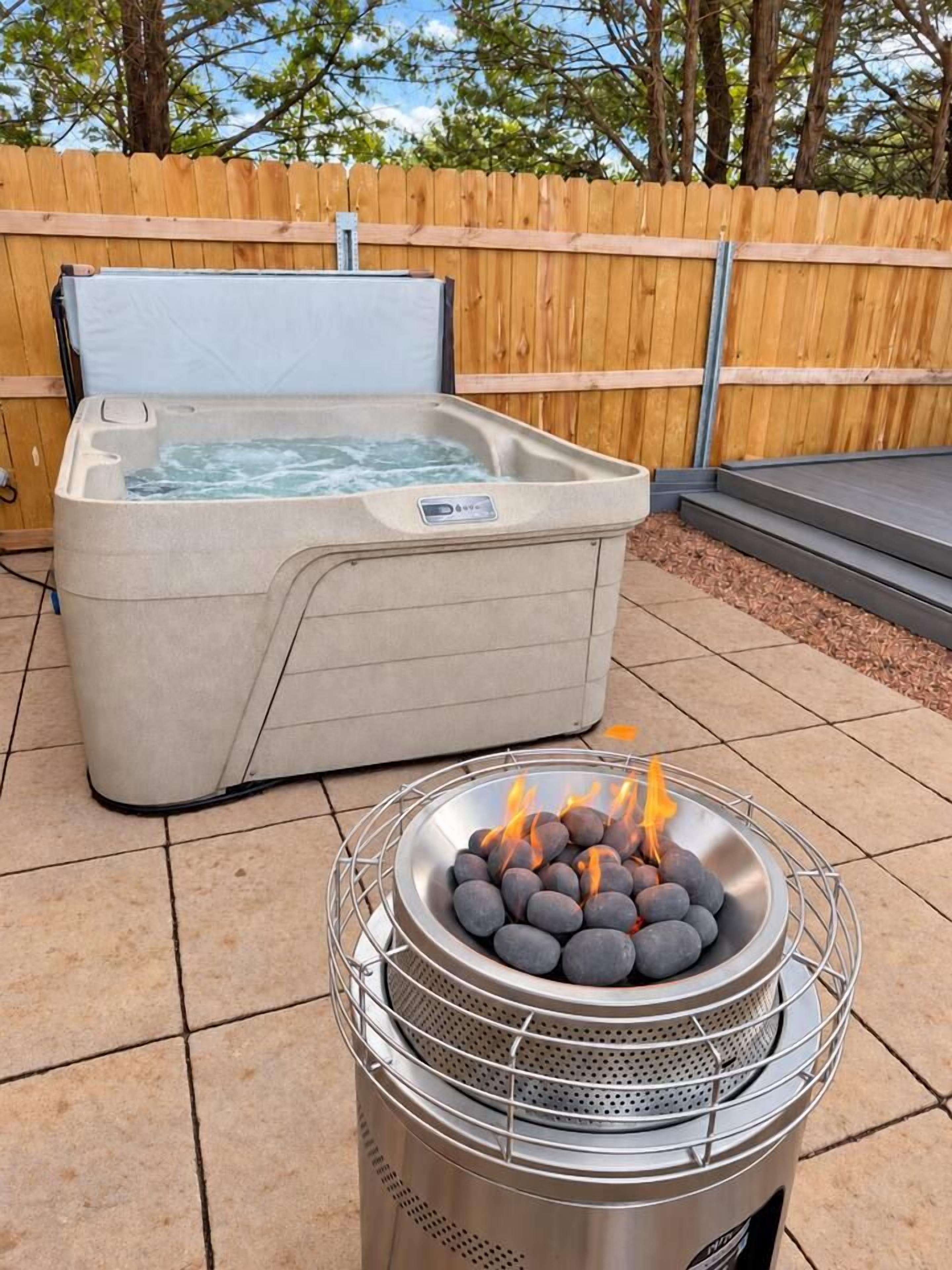 An outdoor hot tub and a fire pit with burning wood.