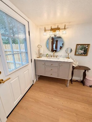 A bathroom with a vanity, a mirror, and a chandelier.