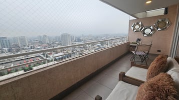 Un balcón con vistas a la ciudad, una mesa con sillas y un muro decorativo.