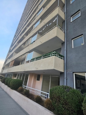 Un edificio residencial de varios pisos con balcones, una entrada con portón y un sendero que lleva a la entrada.