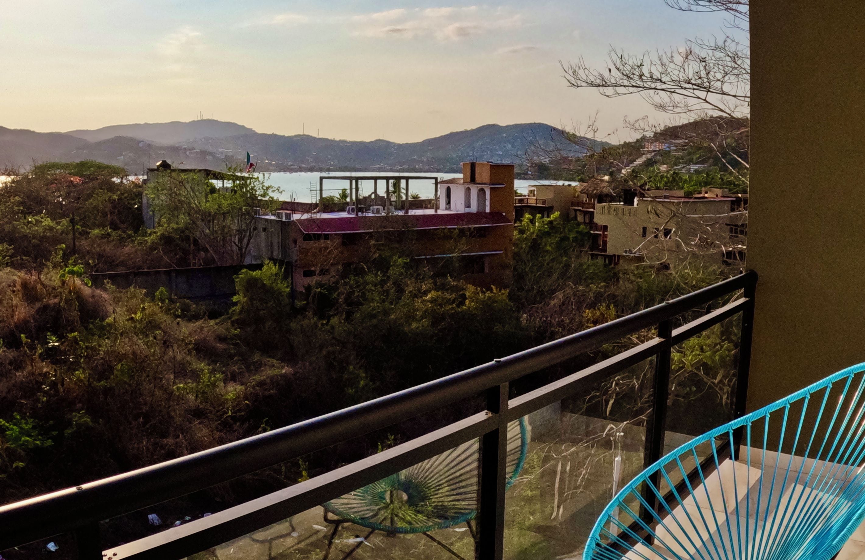 Un balcón con vistas a la costa, incluyendo edificios y montañas.