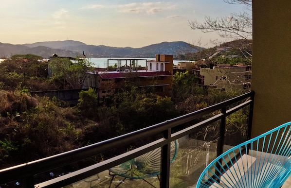 Un balcón con vistas a la costa, incluyendo edificios y montañas.