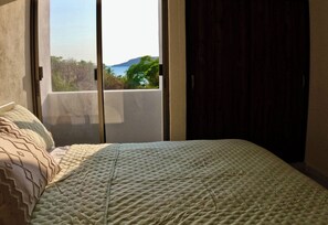 Un dormitorio con cama, ventana y vistas al exterior.