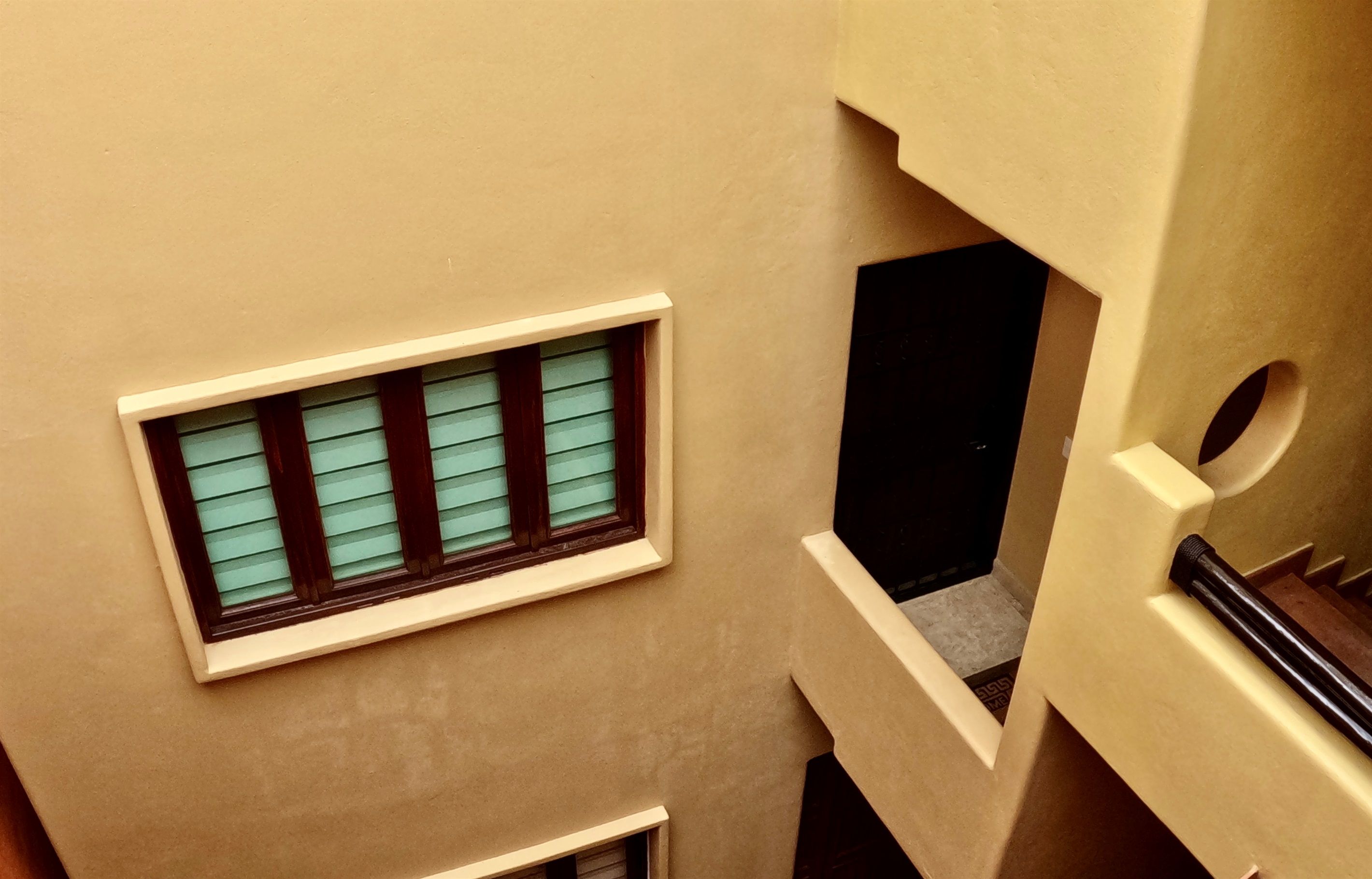 Een gebouw met meerdere verdiepingen, een raam op de bovenverdieping, een deur aan de rechterkant en een trap aan de linkerkant.