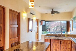 Una cocina con encimeras de granito, armarios de madera, un ventilador de techo y vistas a un paisaje montañoso.