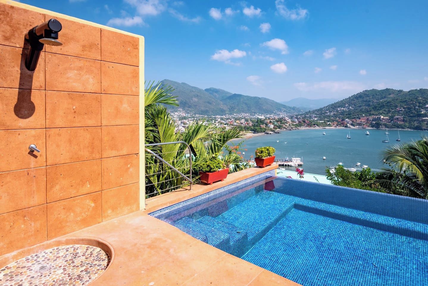 Una piscina con vistas a un pueblo costero y montañas.