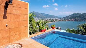 Une piscine avec vue sur une ville côtière et les montagnes.