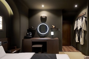 A hotel room with a bed, a desk with a mirror, a coffee machine, and a robe hanging on a rack. - Cave Ryokan Hotel by Anook Gangbuk Suyu (Seoul)