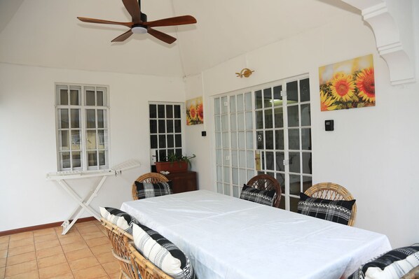 A room with a bed, two chairs, a ceiling fan, a window, and a door with glass panels. - Fantastic 2-bedroom apartment with AC in beautiful Grand Baie (Grand Baie)