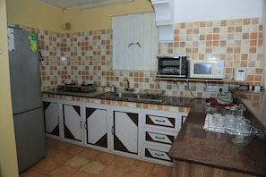 Una cocina equipada con refrigerador, estufa, microondas y pileta.