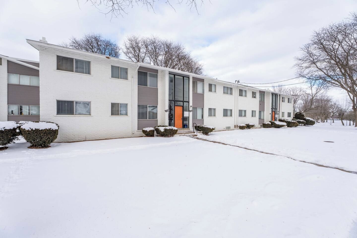 A multi-story residential building with a flat roof, large windows, and a central entrance.