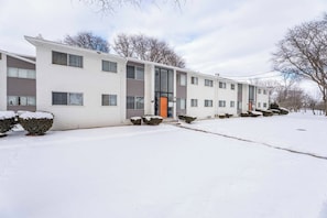 A multi-story residential building with a flat roof, large windows, and a central entrance. - Sand & Sky Suite | ~Smart TV's ~Full Kitchen (Sterling Heights)