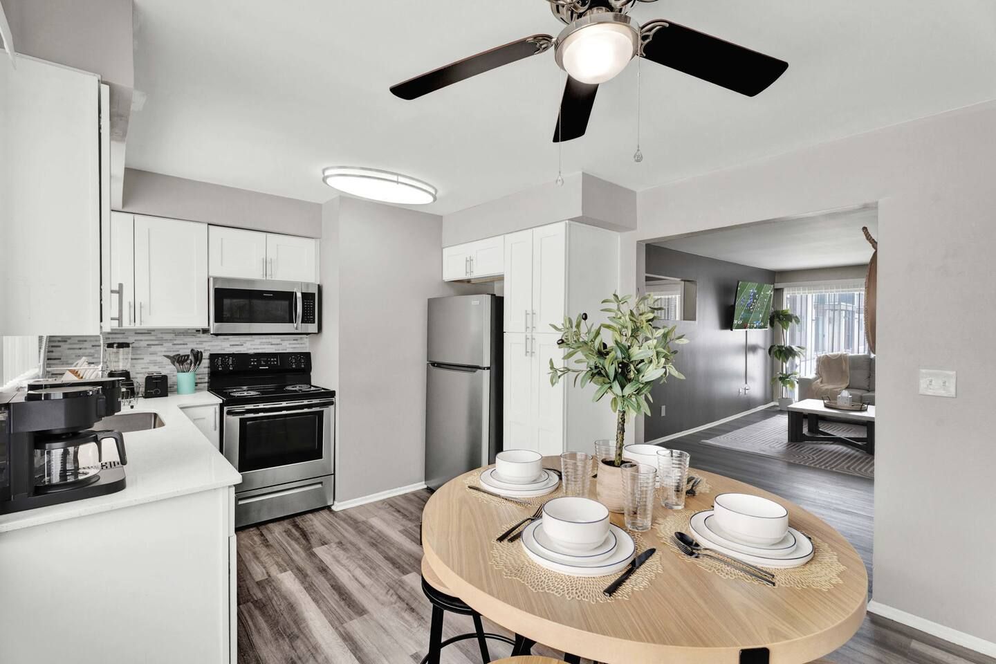 A modern kitchen with a dining area, featuring a central island, built-in appliances, and a ceiling fan.