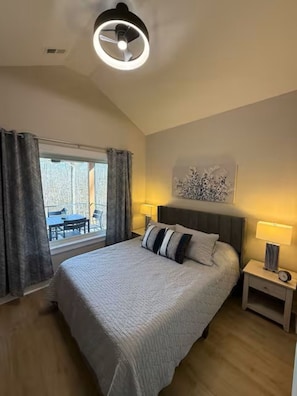 A bedroom with a bed, bedside lamps, a ceiling light, a window with curtains, and a view of the outside. - Nature's Retreat on Lake Norman (Mooresville)