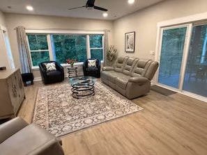 A living room with a sofa, armchairs, a coffee table, and a large window. - Nature's Retreat on Lake Norman (Mooresville)
