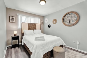 Une chambre à coucher avec un lit, une table de chevet, une lampe et des éléments de décoration murale.